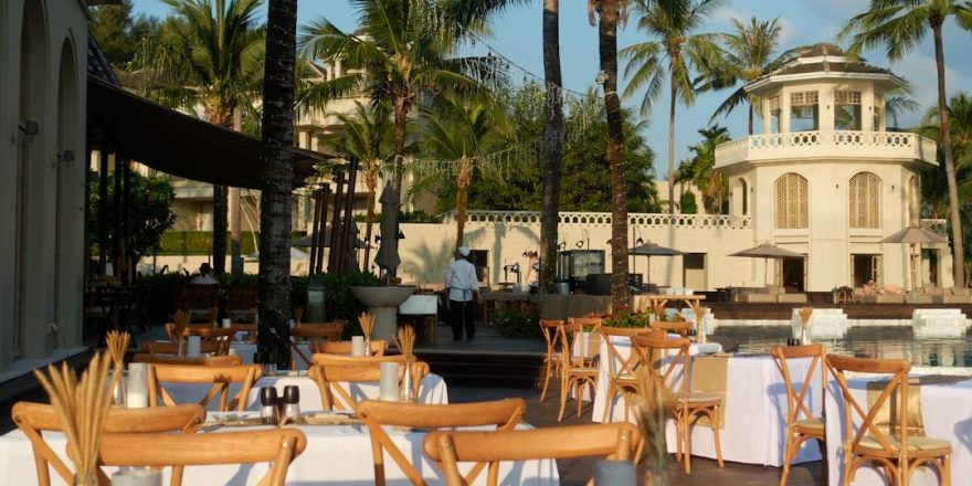 Dukade bord utomhus för att abonnera restaurang vid en pool.